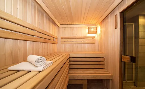 Le sauna en bois clair, serviette pliée sur le banc.