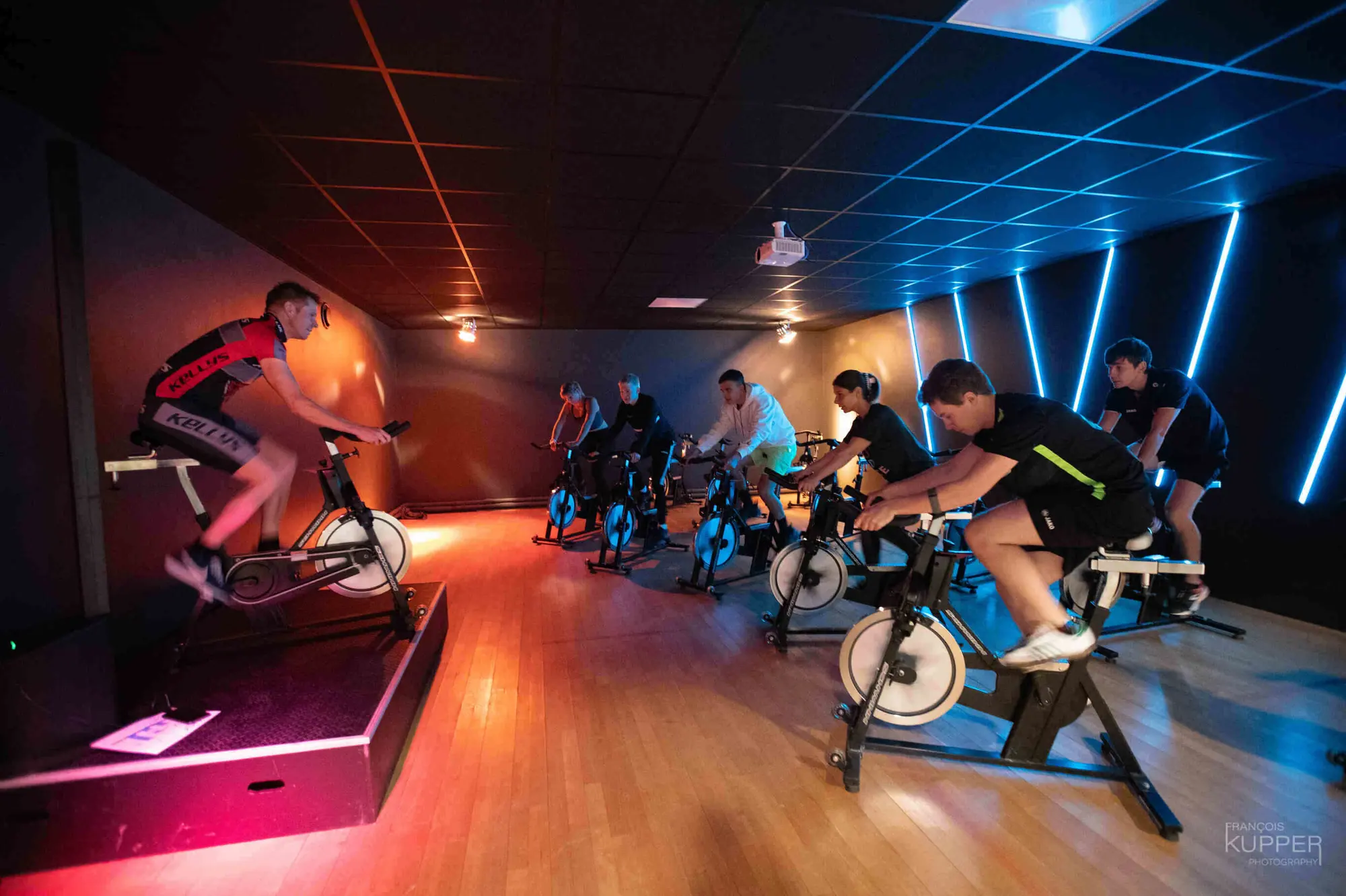 La salle de spinning de Waky, éclairée de néons bleus, pendant un cours.